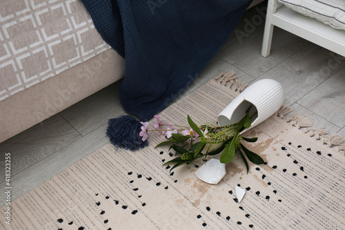 Broken vase and bouquet on floor in room photo