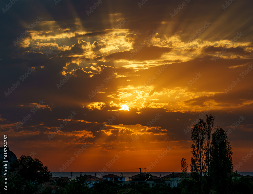 Obraz premium Sunset from Anaxos village over the Aegean sea, golden sunlight rays between the clouds at the end of the day. Vacation holiday on Lesvos an island of Greece.