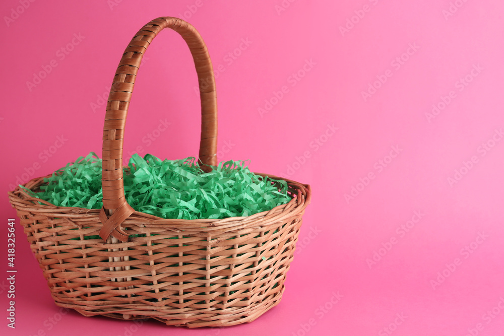 Easter basket with green paper filler on pink background, space for text Easter basket with green paper filler on pink background, space for text