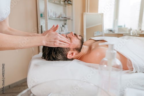 Esthetician or facialist gives a relaxing facial massage to a man