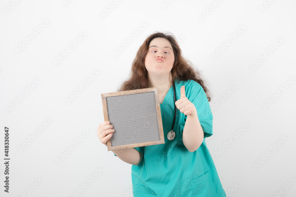 Image of a young girl in green uniform with a frame showing a thumb up Image of a young girl in green uniform with a frame showing a thumb up