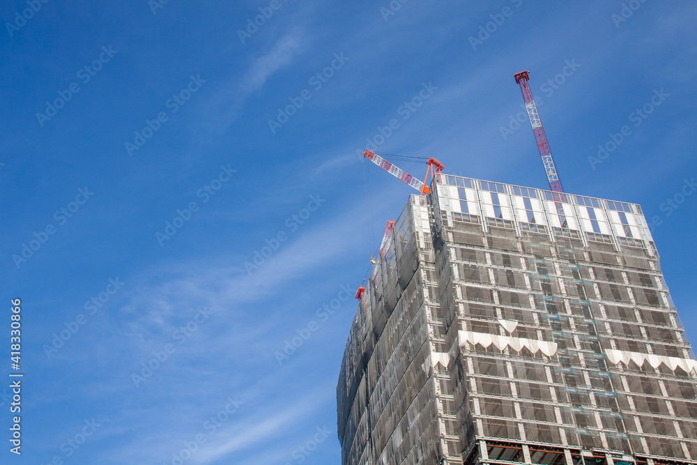High-rise apartment under construction against blue sky