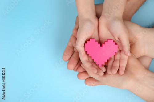 Top view of parents and kid holding pink heart in hands on turquoise background  space for text. Family day