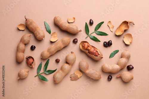 Ripe tamarinds and fresh leaves on beige background, flat lay photo