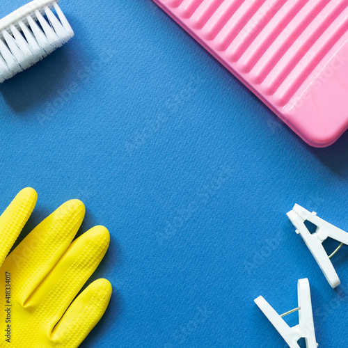 Washboard  clothespins  brush  rubber gloves on blue background. Laundry and cleaning concept. top view  copy space
