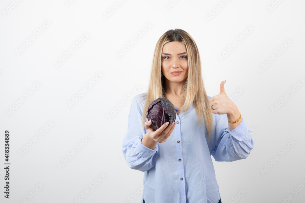 Pretty woman in blue outfit posing with single cabbage on white background Pretty woman in blue outfit posing with single cabbage on white background