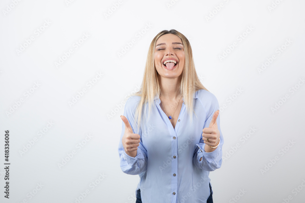 Image of young pretty woman standing and giving thumbs up on white background Image of young pretty woman standing and giving thumbs up on white background