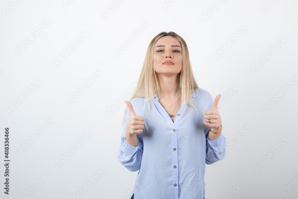 Image of young pretty woman standing and giving thumbs up on white background Image of young pretty woman standing and giving thumbs up on white background