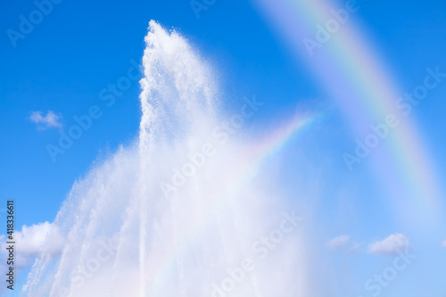 Fountain splashing against blue sky with rainbow