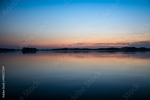 Beautiful Sunset over a lake with clouds and twilight light. Tranquil scene in the natural park landscape.