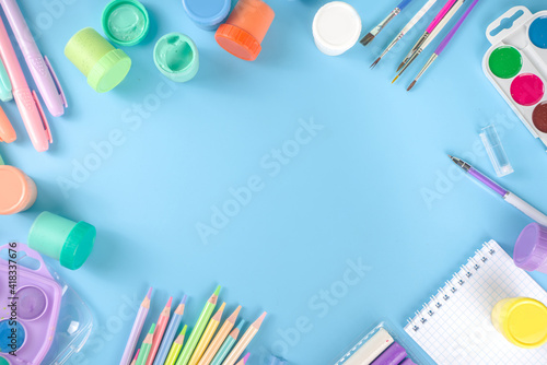 Online study and drawing, distantly painting class. Various colorful stationery and supplies for drawing. paints, pastels, pencils, brushes, tablet on blue background. Flatlay top view copy space