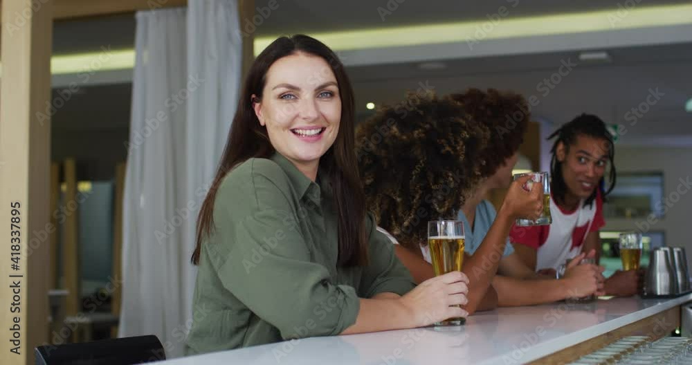 Diverse group of happy friends drinking beers and smiling at a bar Diverse group of happy friends drinking beers and smiling at a bar