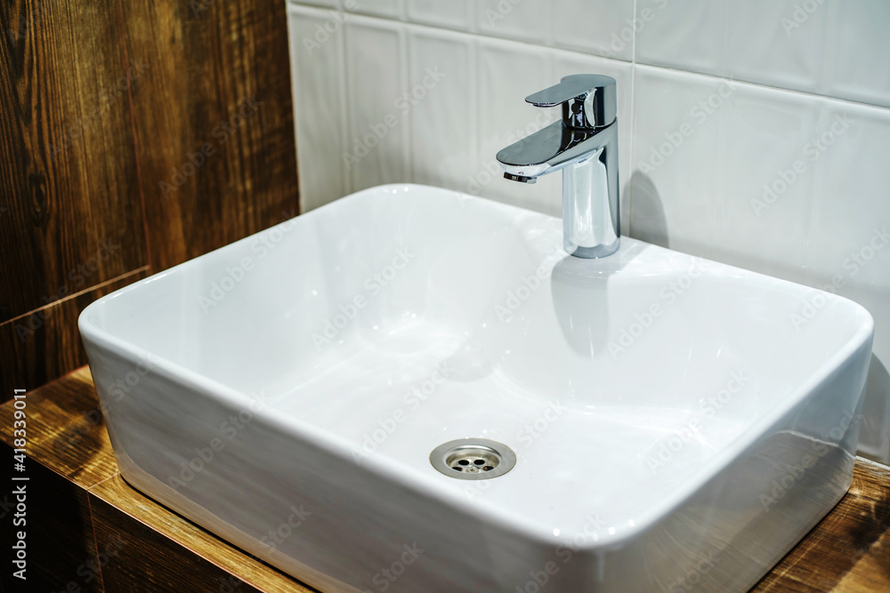 Fototapeta premium White ceramic washbasin and chrome-plated faucet in the bathroom interior. Close-up