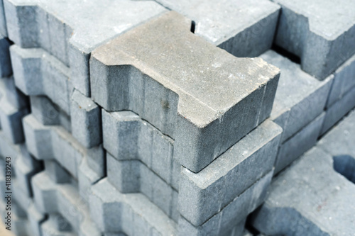 Fototapeta Naklejka Na Ścianę i Meble -  Gray paving stones for the construction of footpaths. Cement material for laying sidewalks in a store warehouse. Trade in blocks with technological slots in the wholesale and retail network. Close-up
