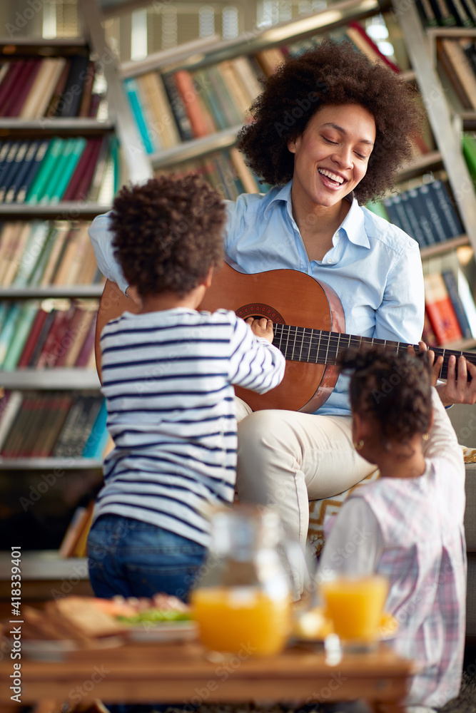 Mom with children enjoys playing the guitar at home. Family, together, love, playtime Mom with children enjoys playing the guitar at home. Family, together, love, playtime