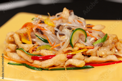 Rice noodles with vegetables on a yellow plate