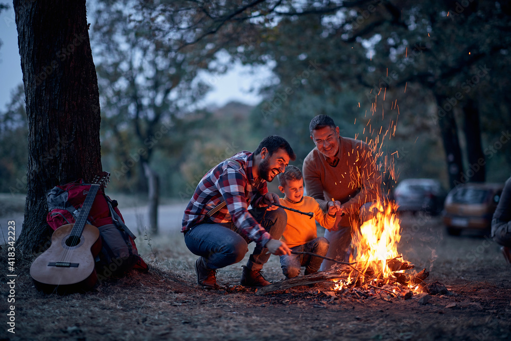 Boy with father and grandfather preparing campfire - obrazy, fototapety, plakaty 
