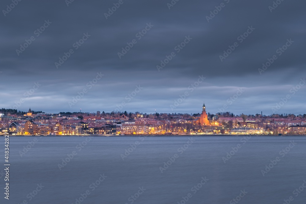 Fototapeta premium View of the center of Östersund just after sunset as seen from the shore of the island of Frösön