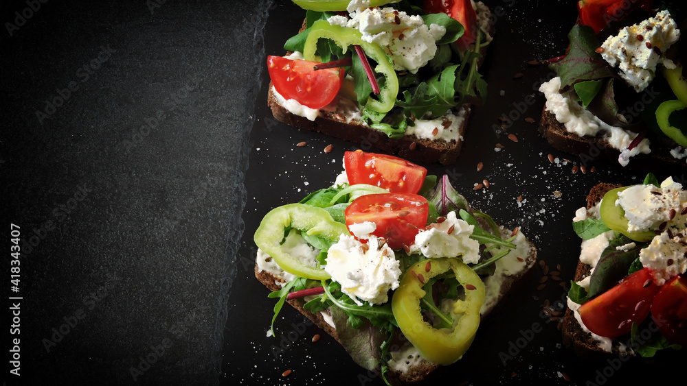 Healthy open sandwiches with salad and white cheese on a black background. The keto diet. Keto snack.