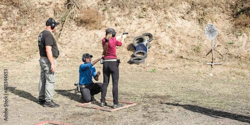 Young girl with coach on tactical gun training classes. Woman with weapon. Outdoor Shooting Range