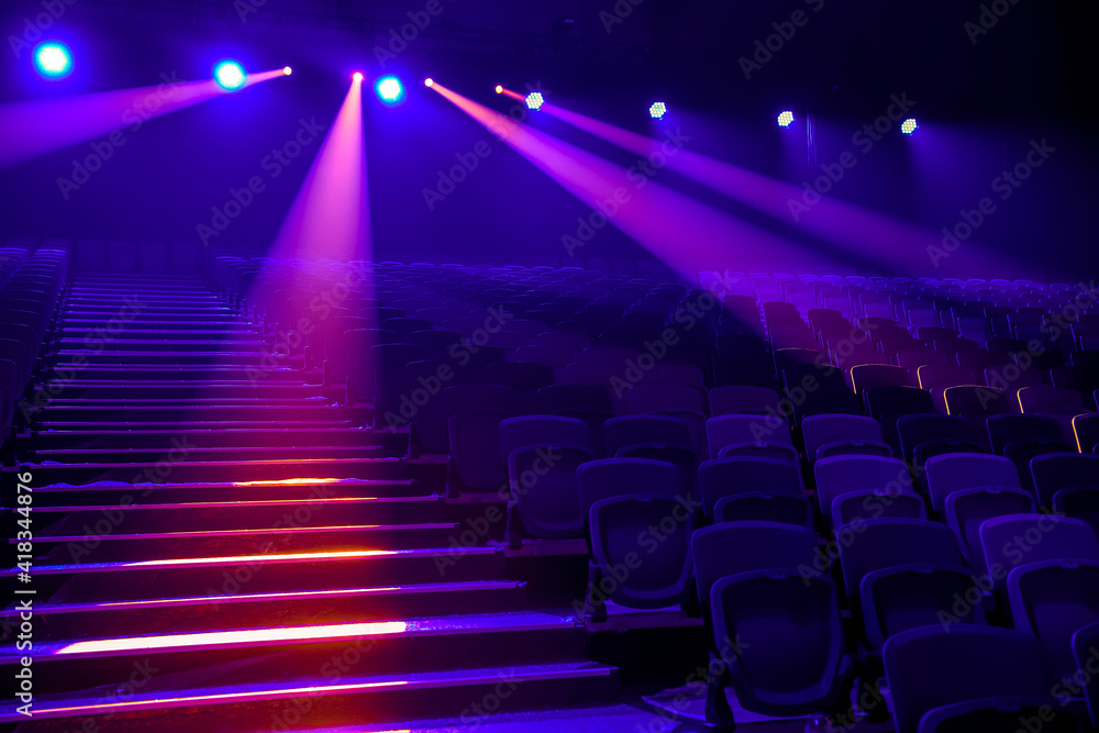 Rows of empty seats in the concert hall in the colored spotlights.