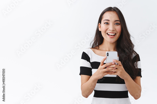 Fotografija Excited, enthusiastic good-looking asian woman in casual outfit holding smartpho