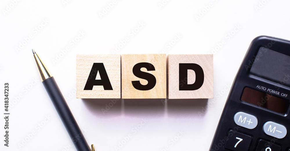 The words ASD Autism Spectrum Disorder is written on wooden cubes between a pen and a calculator on a light background. The words ASD Autism Spectrum Disorder is written on wooden cubes between a pen and a calculator on a light background.