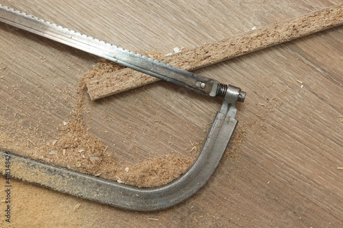 A hacksaw saw lies on the floor with a piece of sawn wood