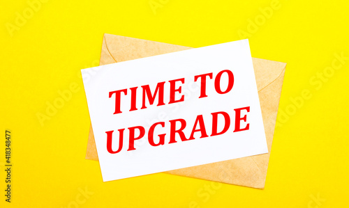On a yellow background, an envelope and a card with the text TIME TO UPGRADE. View from above