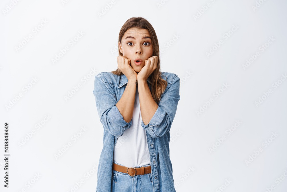 Impressed blond female model gasping and saying wow, leaning on hands and staring amazed at camera, checking out advertisement, standing over white background Impressed blond female model gasping and saying wow, leaning on hands and staring amazed at camera, checking out advertisement, standing over white background