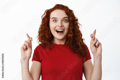 Canvastavla Portrait of excited ginger girl gasping amazed, cross fingers for good luck and