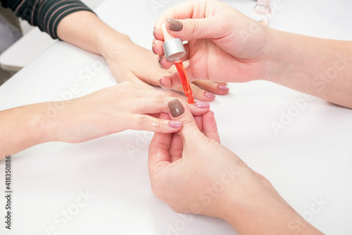 Applying oil to the nail plate in a beauty salon. 