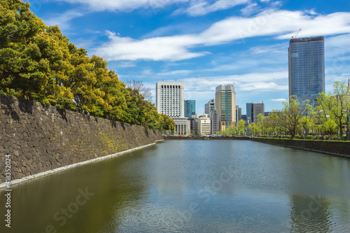 The balance between business and nature in JAPAN. There are tall buildings  a workplace  canal and a park as a resting place. Contemporary between the old city walls and modern town buildings.