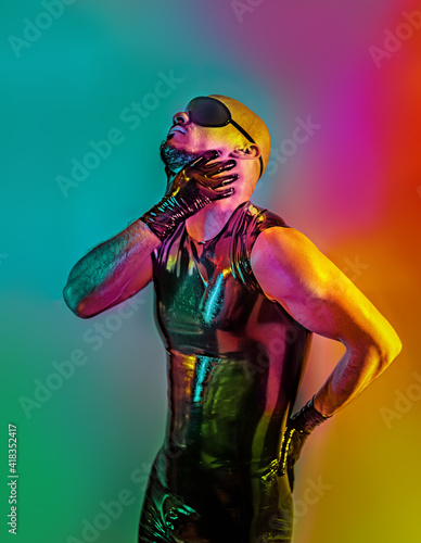 Multicolored creative artistic portrait of a rubber fetish, latex young man with fashion leather outfit on a colorful rainbow lighting and background. photo