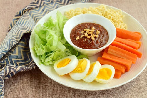 Gado-gado, traditional Indonesian salad with peanut sauce on brown background