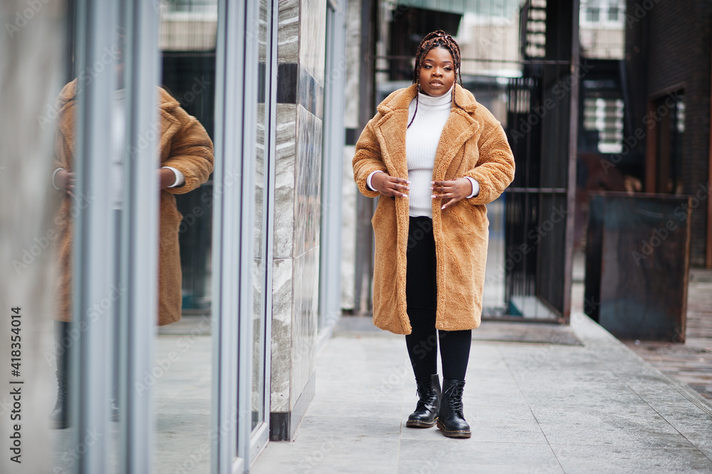 Glamorous african american woman in warm fur coat, eyeglasses pose at street.