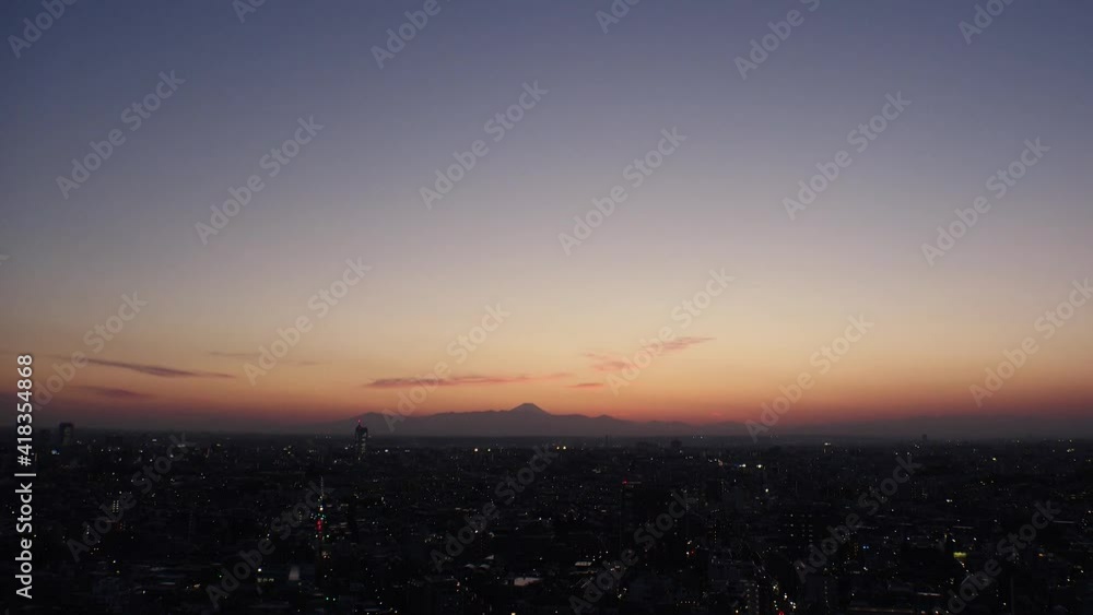 TOKYO, JAPAN : Aerial high angle sunset CITYSCAPE of TOKYO and MOUNT FUJI. View of sinking sun and buildings. Japanese urban city life and metropolis concept. Time lapse zoom in shot dusk to night. TOKYO, JAPAN : Aerial high angle sunset CITYSCAPE of TOKYO and MOUNT FUJI. View of sinking sun and buildings. Japanese urban city life and metropolis concept. Time lapse zoom in shot dusk to night.