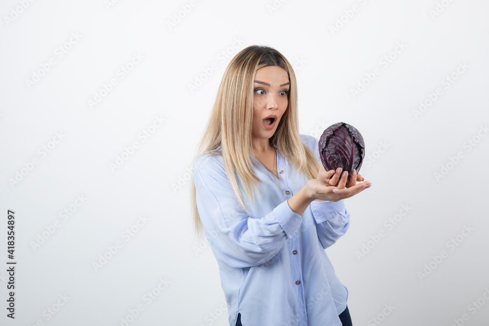 Pretty woman in blue outfit looking at purple cabbage on white background Pretty woman in blue outfit looking at purple cabbage on white background