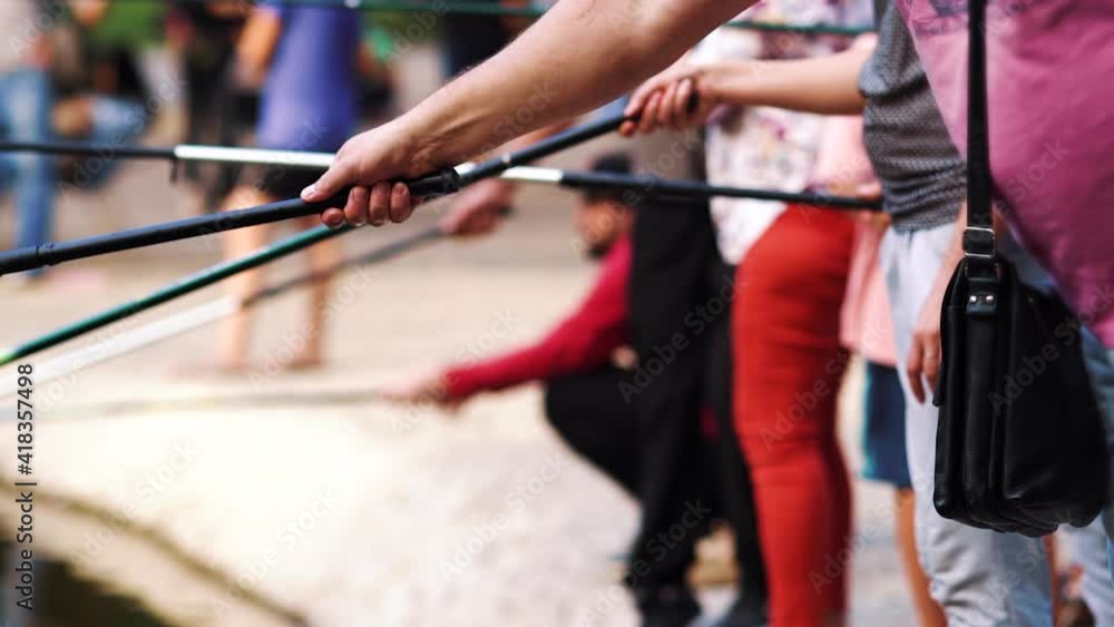 Hands of men and women holding fishing rods while standing on bank of river, blurred background. Partial view of people enjoying fishing in summer. Concept of hobby Hands of men and women holding fishing rods while standing on bank of river, blurred background. Partial view of people enjoying fishing in summer. Concept of hobby