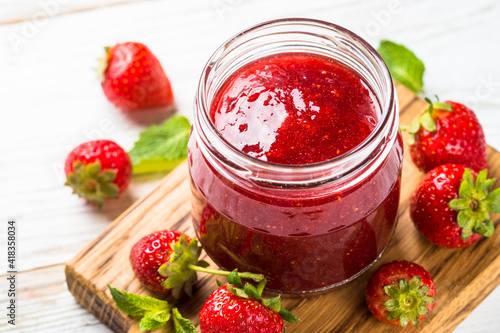 Strawberry jam in the glass jar with fresh berries. Close up.