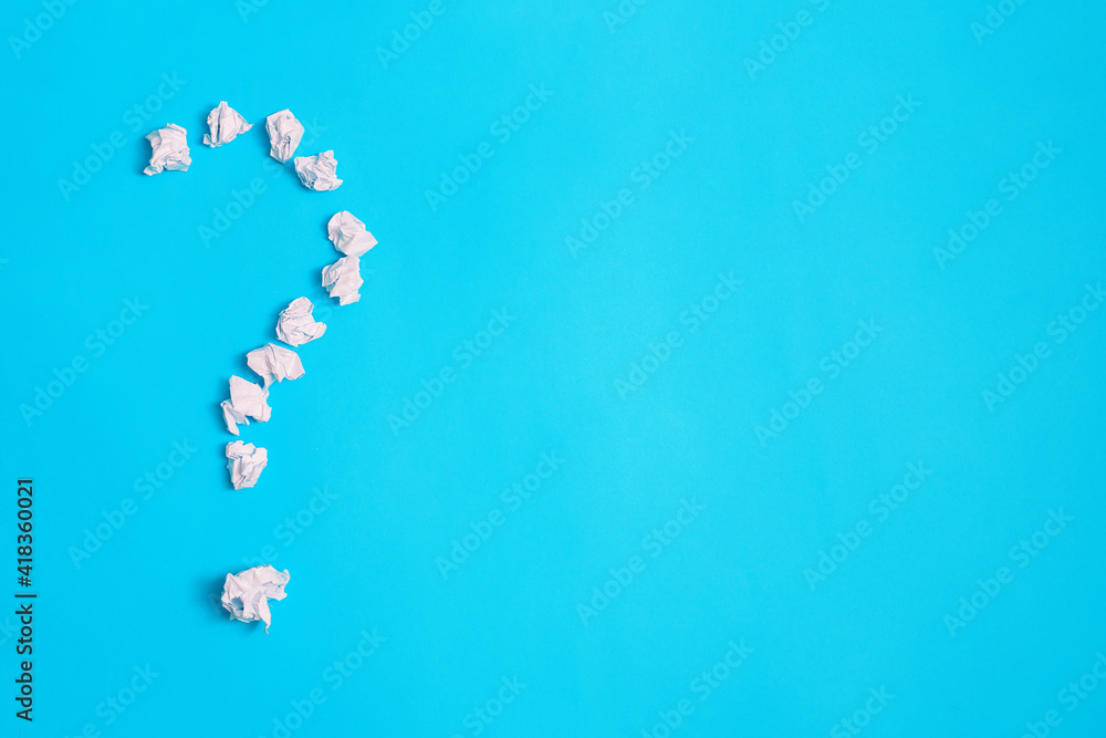 A question mark on a blue background. The question mark is made of crumpled paper. A question mark on a blue background. The question mark is made of crumpled paper.