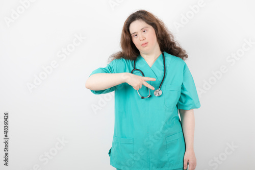 Young female doctor with down syndrome giving signs on white background