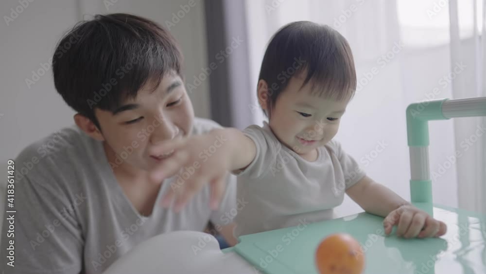 Lovely family: Young asian father and active daughter playing with an orange ball on colorful toy slider, playful preschooler brushed off a toy happily, let it slide down to floor cheerfully, Lovely family: Young asian father and active daughter playing with an orange ball on colorful toy slider, playful preschooler brushed off a toy happily, let it slide down to floor cheerfully,