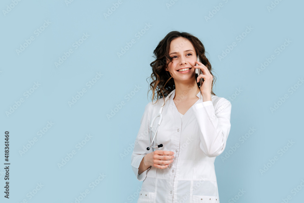 Dreamy social female nurse smiling and talking on the phone. Over blue background. She wears white robe and stethoscope. Dreamy social female nurse smiling and talking on the phone. Over blue background. She wears white robe and stethoscope.