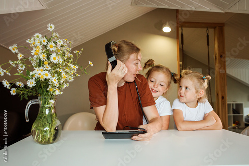 Mom is trying to work or comminicate online, her two daughters interrupting her
