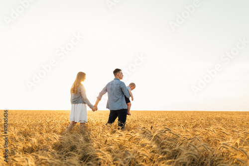 Happy family in wheat field at sunset having a great time together