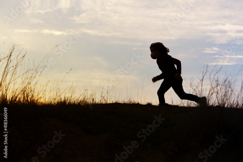 silhouette of girl running across the horizon at sunset. Slight motion blur.