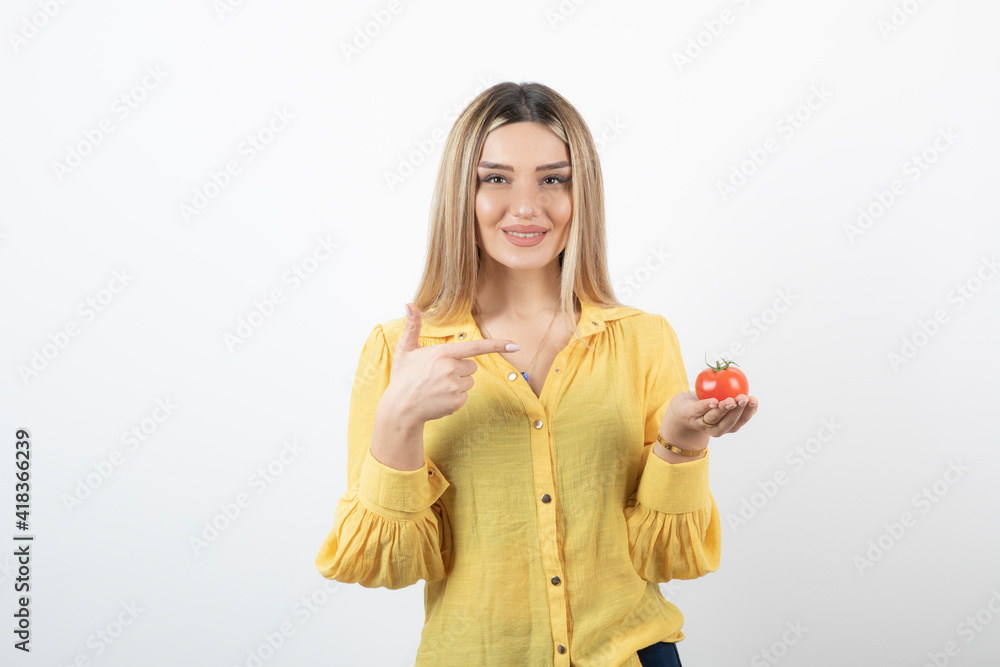 Smiling woman holding red tomato and posing on white background Smiling woman holding red tomato and posing on white background