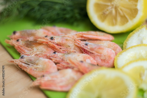 shrimps on a green board with lemon and dill