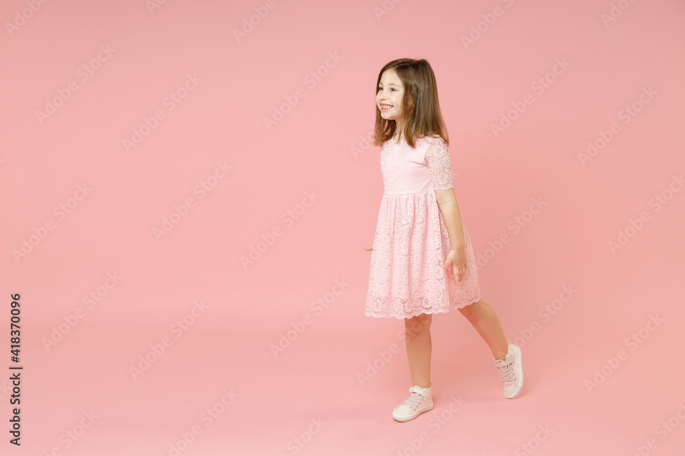 Full body length little cute kid girl 5-6 years old wears rosy dress have fun walk go step isolated on pastel pink background child studio portrait. Mother's Day love family people lifestyle concept. Full body length little cute kid girl 5-6 years old wears rosy dress have fun walk go step isolated on pastel pink background child studio portrait. Mother's Day love family people lifestyle concept.